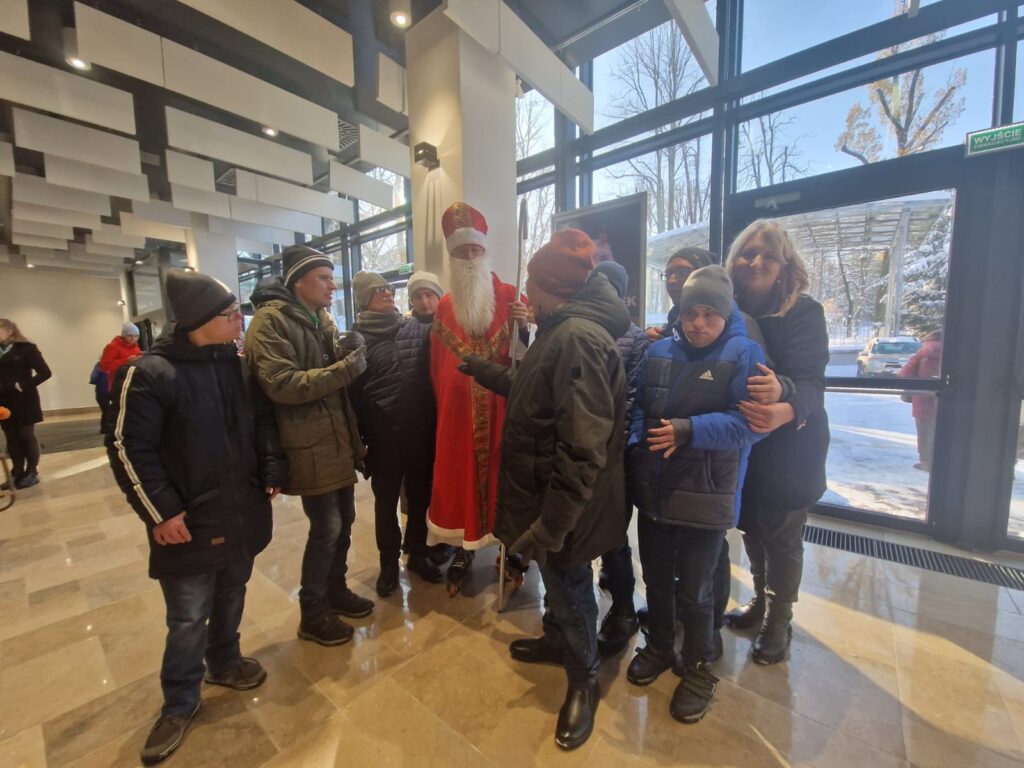 Zdjęcie grupy osób witających się z mężczyzną w stroju Mikołaja. 