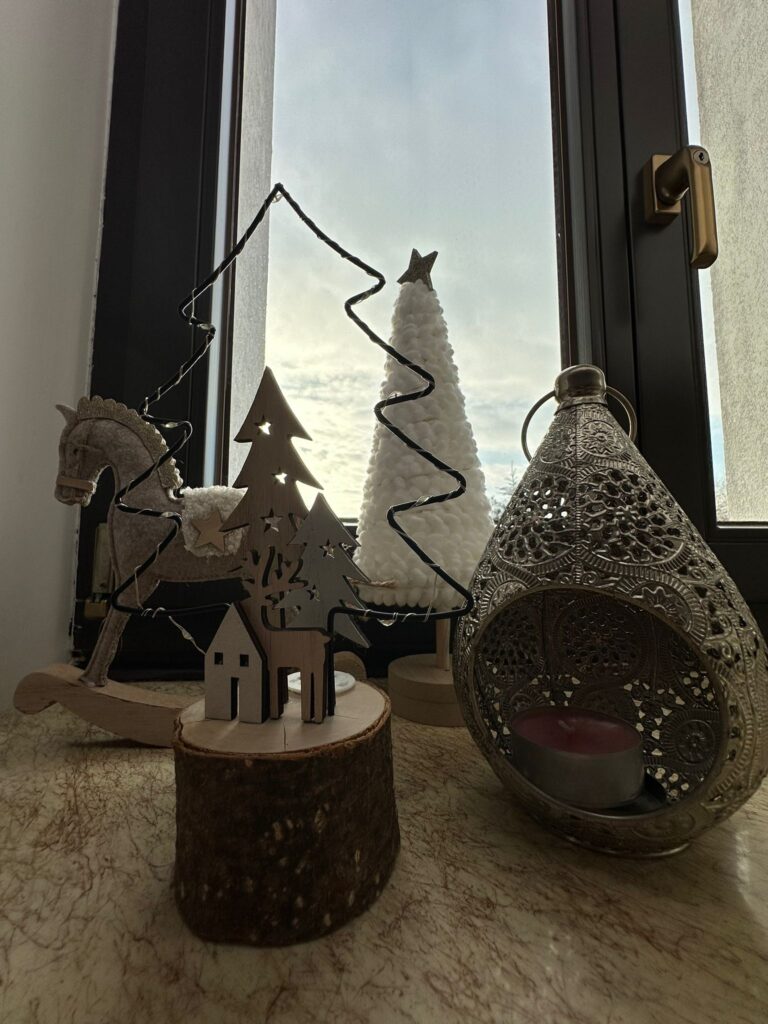 Dekoracja świąteczna: dekoracja na parapecie okna: lampion, drewniane choineczki i mini konik na biegunach. 