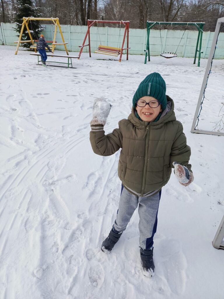 Roześmiany chłopak podczas zabawy na śniegu 