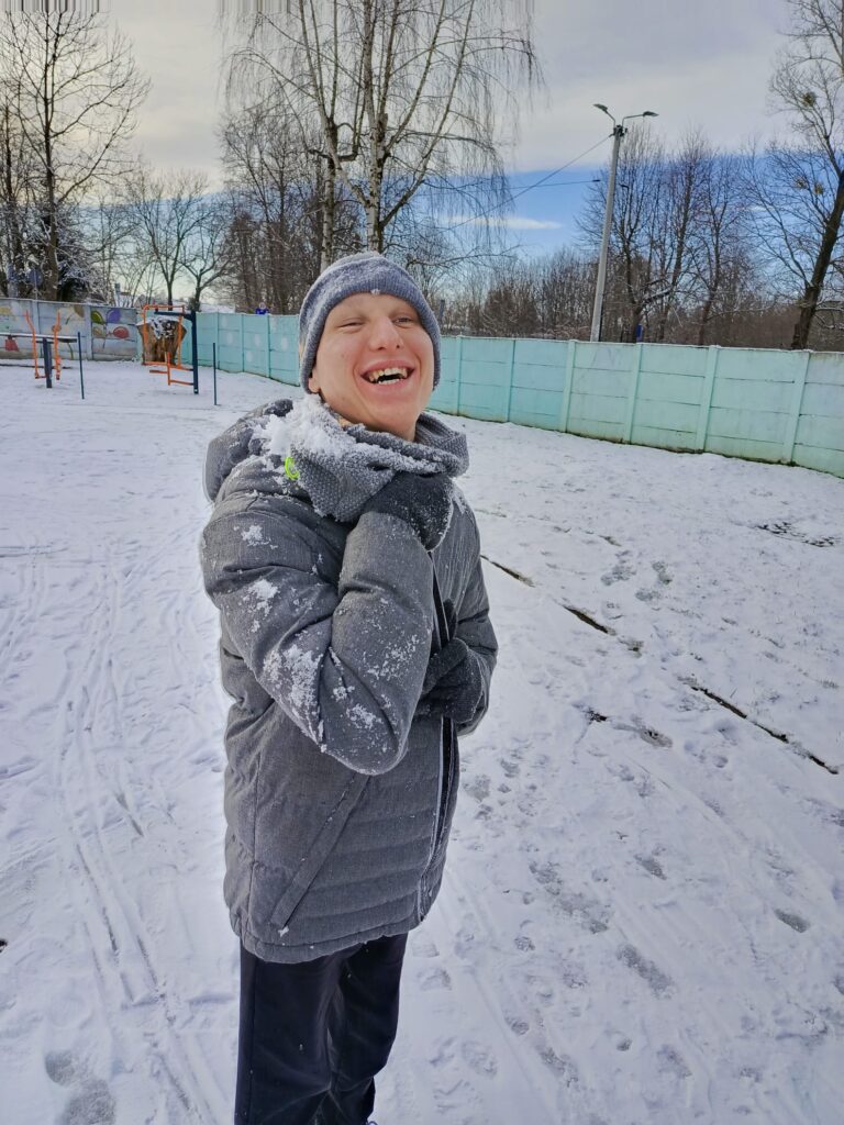 Roześmiany chłopak podczas zabawy na śniegu 