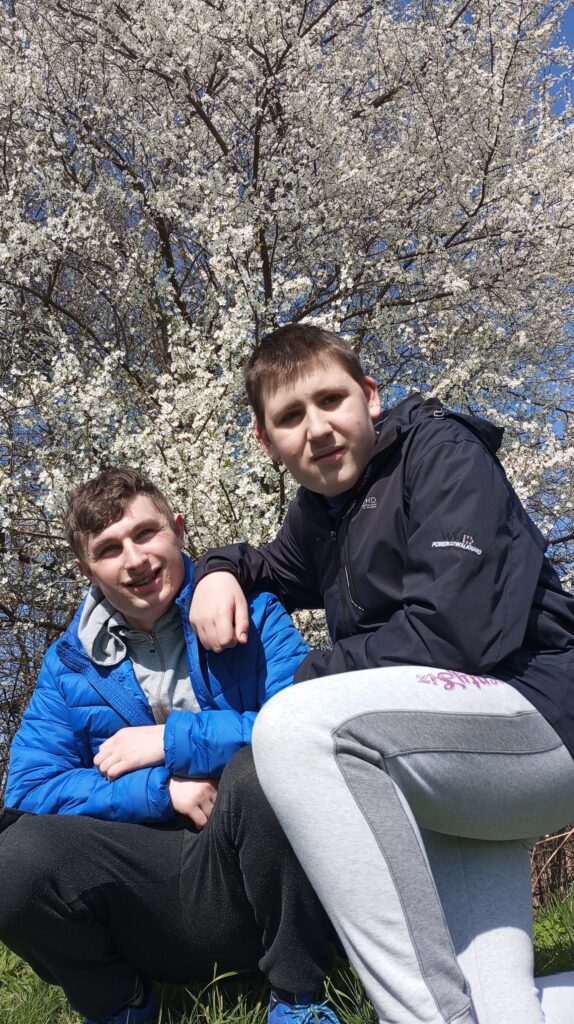 Dwoje chłopców na tle kwitnącej czereśni. 