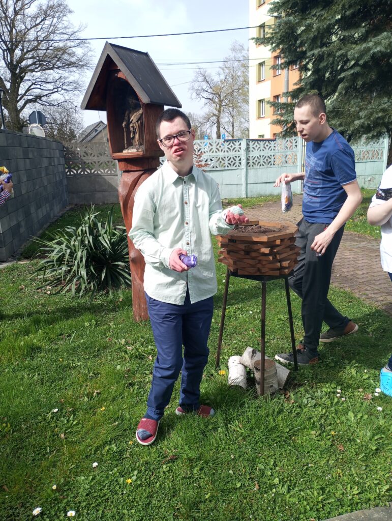 Chłopcy zbierający czekoladowe  jajka i zajączki w ogrodzie 