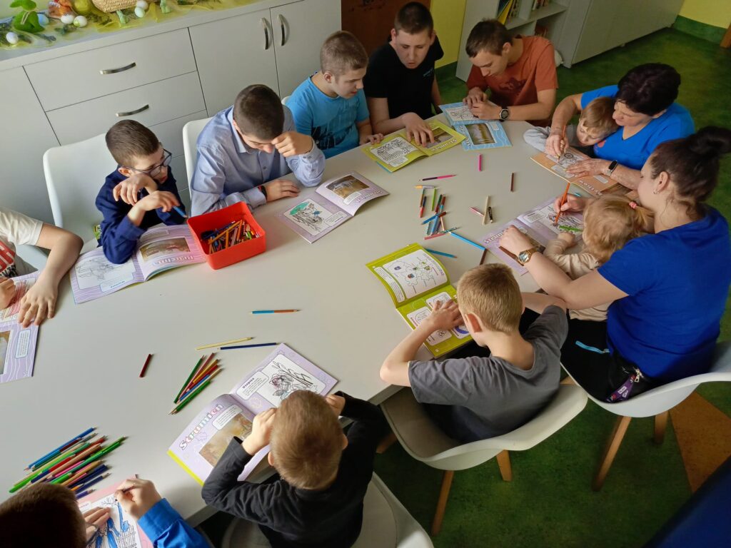 Grupa osób wokół stołu - kolorująca książeczki 
