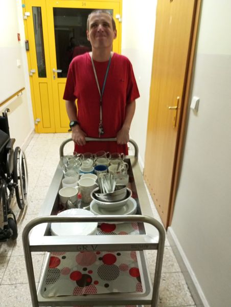 Chłopak wiozący wózek z naczyniami 