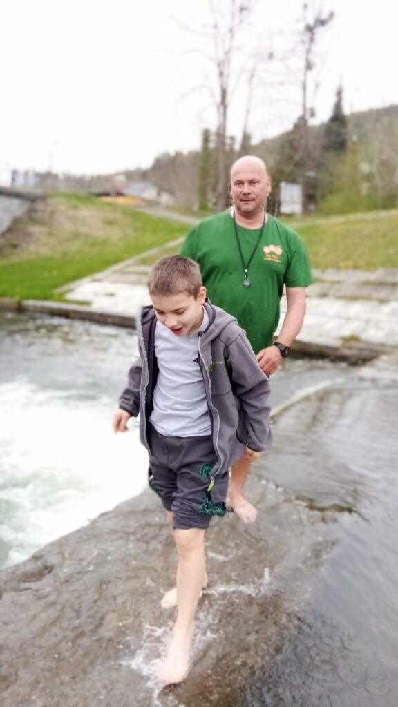 chłopiec i mężczyzna spacerujący boso po rzece 