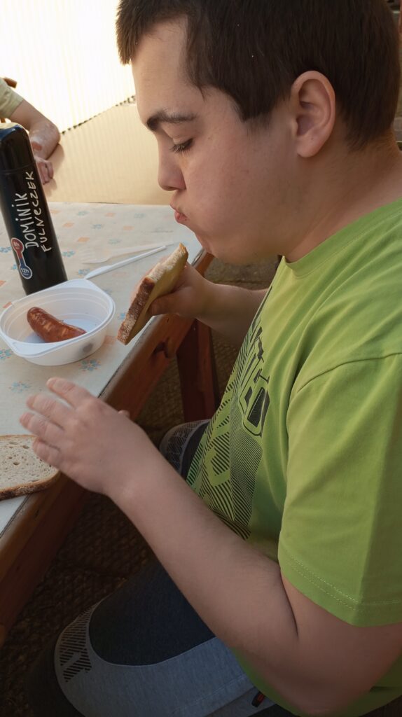 Chłopiec jedzący grillowaną kiełbasę. 